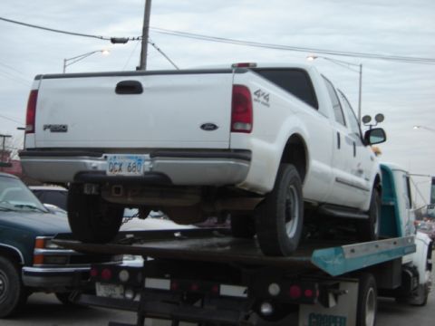 1992 Ford Bronco - A white Ford F-250 pickup truck is being transported on a flatbed tow truck.
