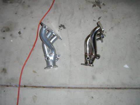 1996 Ford Probe - Comparison of two exhaust manifolds, one with a silver finish and the other with a chrome finish.