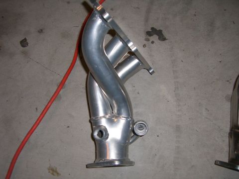 1996 Ford Probe - An exhaust manifold is shown on a concrete surface, with a red cable nearby.