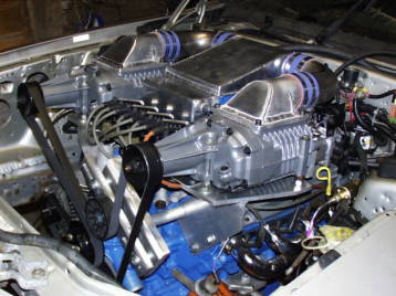 1993 Ford Taurus - Close-up view of a modified engine bay a complex setup of superchargers and associated plumbing.