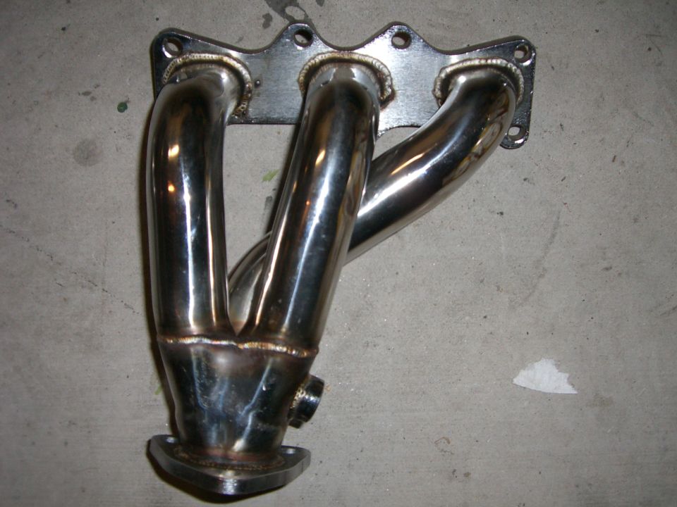Exhaust manifold with four pipes merging into one, mounted on a metal flange