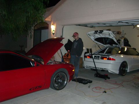 1996 Ford Probe - Two sports cars, one red and one white, are parked in a garage with their hoods and trunks open, suggesting maintenance or work is being do…