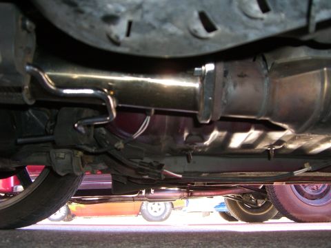 1996 Ford Probe - Underneath view of a car's exhaust system and suspension, with multiple vehicles in the background.