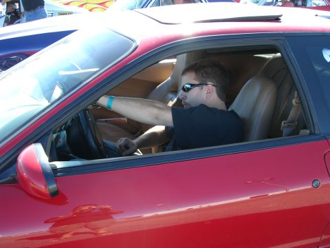 1996 Ford Probe - Driver in a red car with a sunroof, seen from the side.