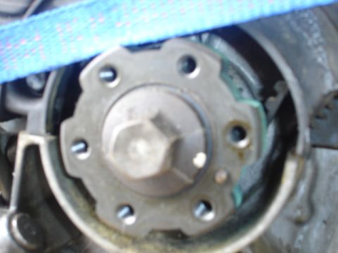 1993 Mazda MX-3 - A close-up view of a mechanical engine component, possibly a timing pulley or gear, with visible bolts and a central hex nut.