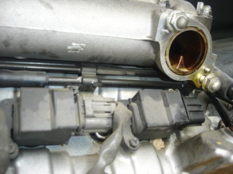 1993 Mazda MX-3 - Detail shot of engine parts, including connectors and part of the intake manifold, showing wear and oil residue.