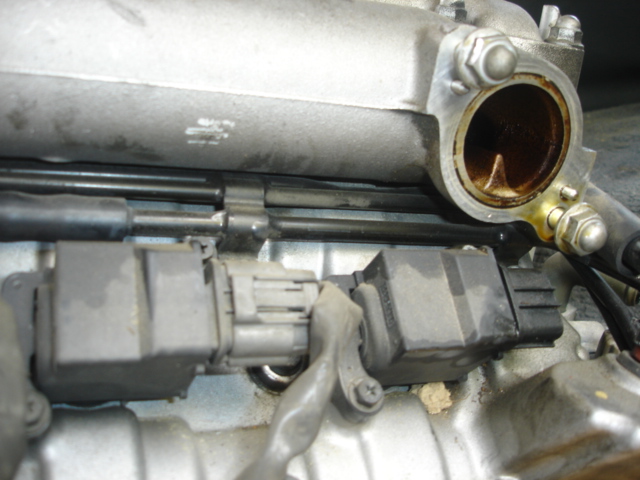 Close-up of engine intake manifold with open port and internal rust discoloration