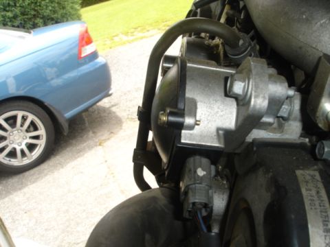 1993 Mazda MX-3 - A close-up view of an engine part is shown, with a blue car in the background.