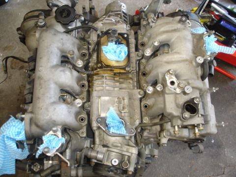 1993 Mazda MX-3 - Engine assembly with blue rags stuffed into openings, showing intake manifolds and central casing.