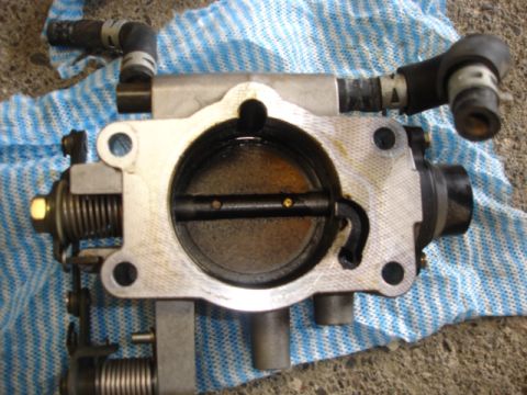 1993 Mazda MX-3 - A throttle body assembly, likely removed for cleaning or repair, rests on a striped cloth.