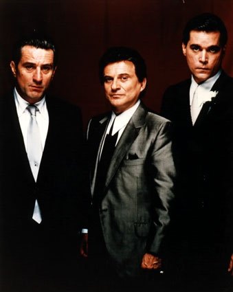 1986 Ford Bronco - A publicity still showing three men in dark suits and ties posed shoulder to shoulder against a red backdrop; no vehicle or vehicle part ap…