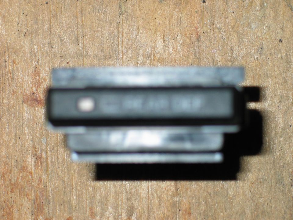 Black electronic part with visible text on a wooden surface