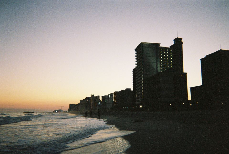 Beach scene with ocean waves and buildings at sunset