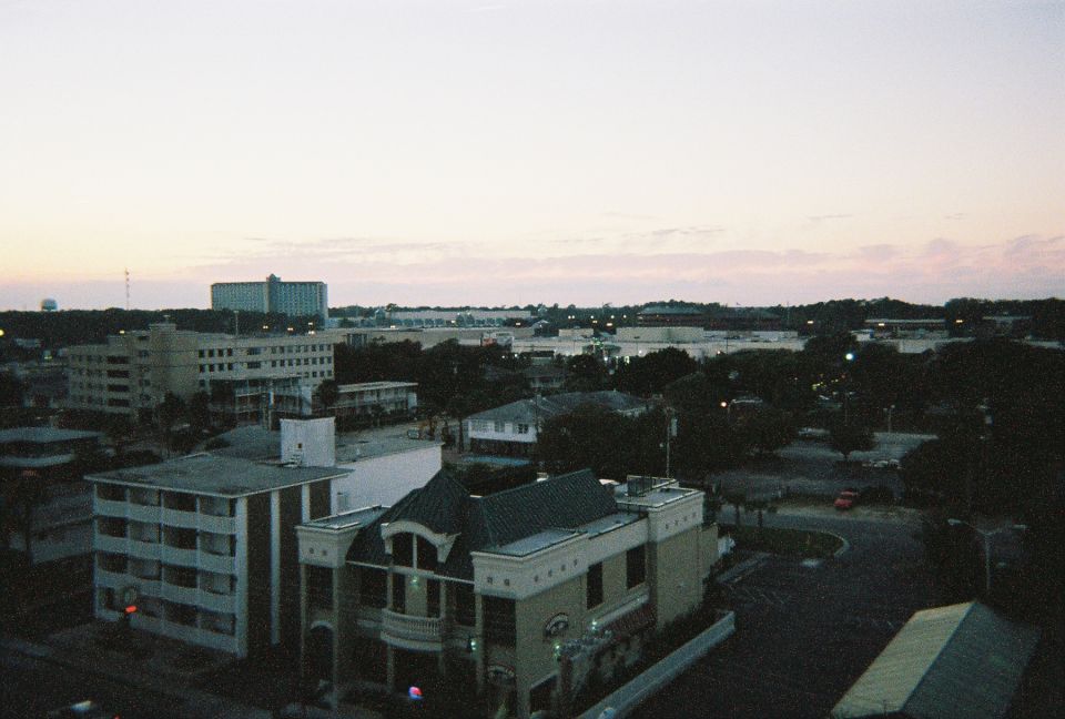 Cityscape at dusk with buildings and trees, Supermotors logo visible