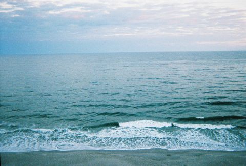 1991 Ford Probe - The vast ocean meets the shore with gentle waves under a pale sky.