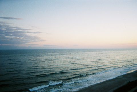 1991 Ford Probe - A tranquil ocean scene with gentle waves lapping the shore at dusk, under a soft, pastel-colored sky.