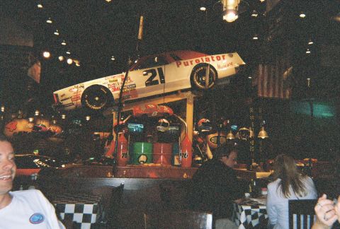 1991 Ford Probe - A race car is displayed indoors, suspended above patrons dining at tables.