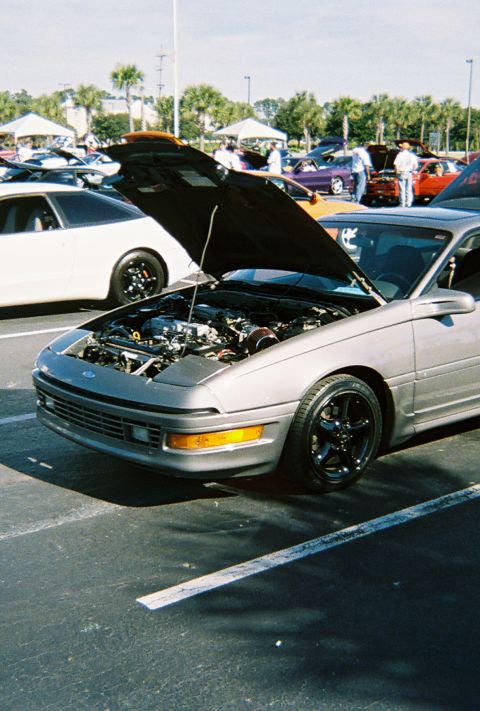 1991 Ford Probe - A silver 1991 Ford Probe is parked with its hood up, revealing the engine, alongside other vehicles.