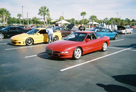 1991 Ford Probe - A red 1991 Ford Probe is parked in a lot, with several other vehicles visible around it.