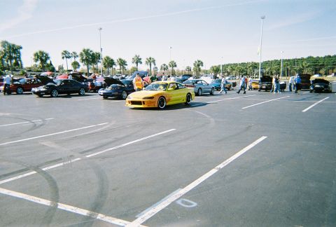 1991 Ford Probe - A car meet with multiple vehicles parked in an outdoor lot on a sunny day.