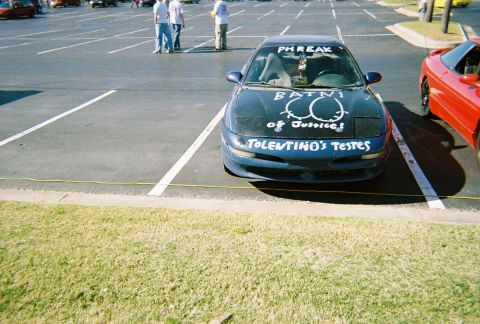 1991 Ford Probe - A blue coupe is parked in a lot with graffiti on its hood and windshield.