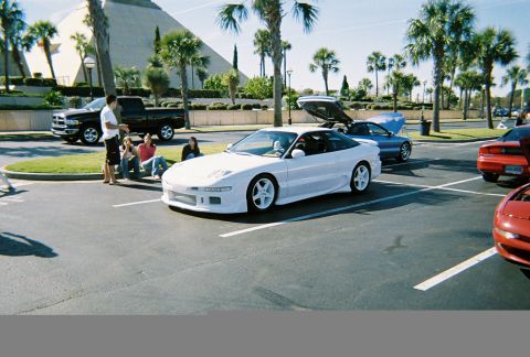 1991 Ford Probe - White 1991 Ford Probe in parking lot with other vehicles and people.