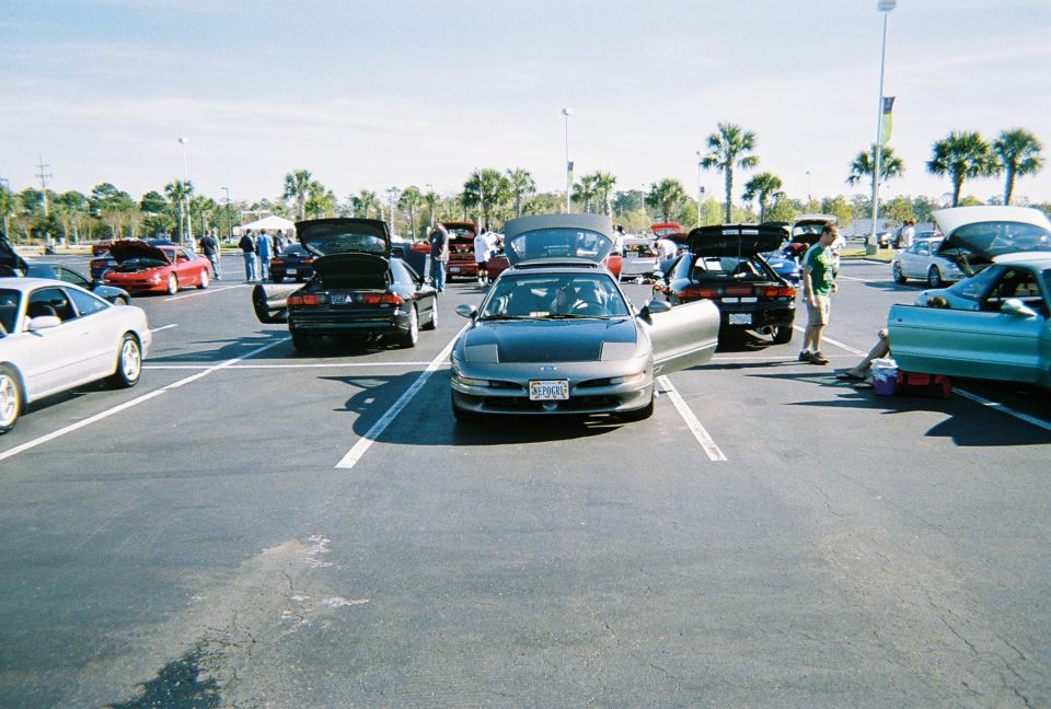 Several Ford Probe cars parked in a lot, some with hoods and doors open. The front car is gray