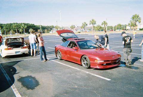 1991 Ford Probe - A red 1991 Ford Probe is parked with its trunk open, while another white car with its trunk open is visible in the background.