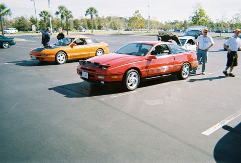 1991 Ford Probe - Two Ford Probes are parked in a lot with people standing around them.