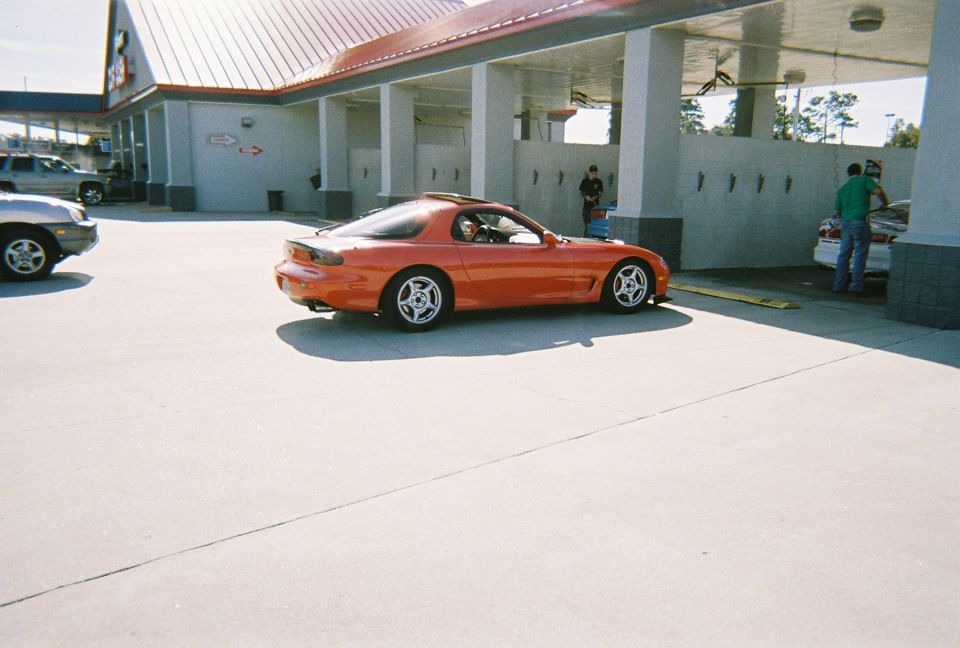 Orange Mazda RX-7 parked at a car wash