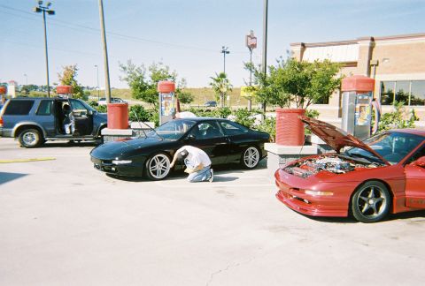 1991 Ford Probe - A blue SUV, a black 1993 Ford Probe, and a red 1993 Ford Probe with its hood open are parked at a car wash.