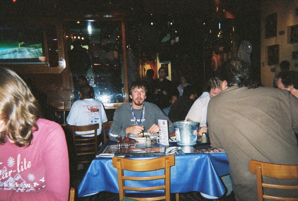 People sitting at tables in a dimly lit restaurant, some eating