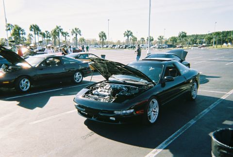 1991 Ford Probe - A black coupe with its hood open is parked in a lot, with other cars and palm trees in the background.