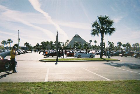 1991 Ford Probe - Cars gathered in a parking lot with a pyramid structure visible in the distance.