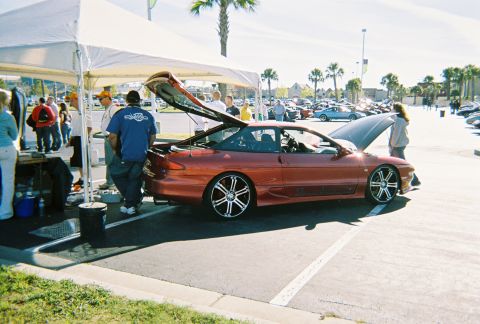 1991 Ford Probe - An orange Ford Probe is displayed with its hood and trunk open at an outdoor event.