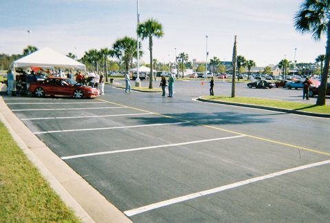 1991 Ford Probe - A red coupe is displayed under a tent at an outdoor event with other vehicles in the background.