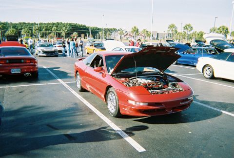1991 Ford Probe - A red 1991 Ford Probe is displayed with its hood open, revealing the engine bay at an outdoor event.