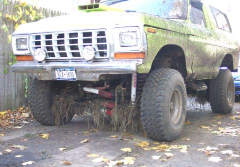 1978 Ford Bronco - This heavily modified 1978 Ford Bronco is covered in mud and vegetation, suggesting it has seen off-road use.