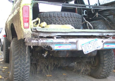 1978 Ford Bronco - This heavily modified off-road vehicle, covered in mud, shows its rear end with a spare tire visible in the cargo area and a license plate…
