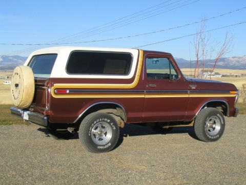 1979 Ford Bronco - This 1979 Ford Bronco features a two-tone maroon and white paint scheme with a distinctive side stripe and a rear-mounted spare tire.