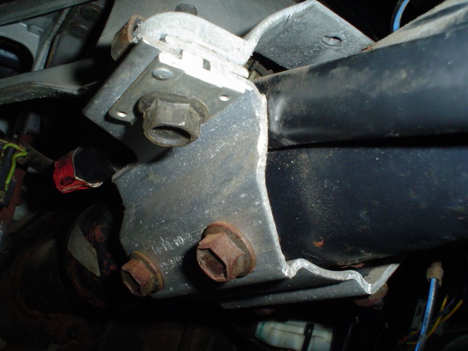 Close-up of a metal bracket attached to a black tube, with bolts and wiring visible
