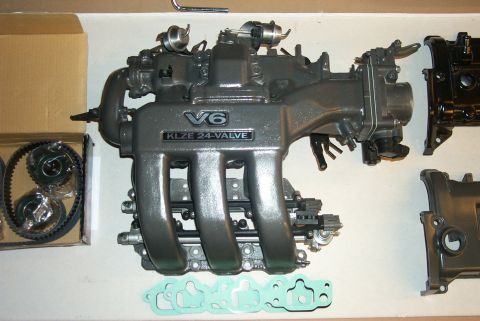 1996 Ford Probe - Engine parts including a V6 KLZE 24-VALVE intake manifold, timing belt kit, and gaskets are laid out.