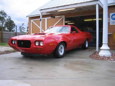 1972 Ford Ranchero - This red 1972 Ford Ranchero features a distinctive hood scoop and a custom front grille, parked in front of a garage.
