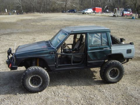 1992 Ford Bronco - Custom Jeep Cherokee XJ pickup truck modified for off-road use with a roll cage and large tires.
