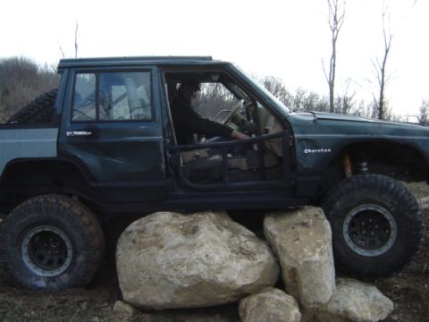 1992 Ford Bronco - A modified green Jeep Cherokee navigates over large rocks, its off-road capabilities.