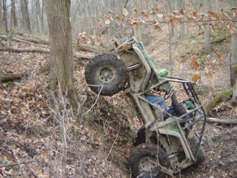 1992 Ford Bronco - An off-road buggy has tipped onto its side in a wooded area, with the driver still in the seat.
