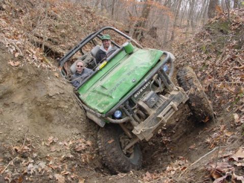 1992 Ford Bronco - Two people navigate a challenging muddy incline in a modified off-road vehicle.