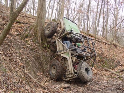 1992 Ford Bronco - An off-road buggy is stuck against a tree on a steep, wooded incline.
