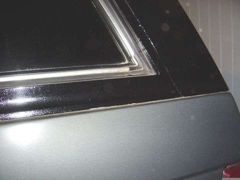 1986 Ford Bronco - Detail of a car door panel showing black and silver paint with a chrome trim piece.