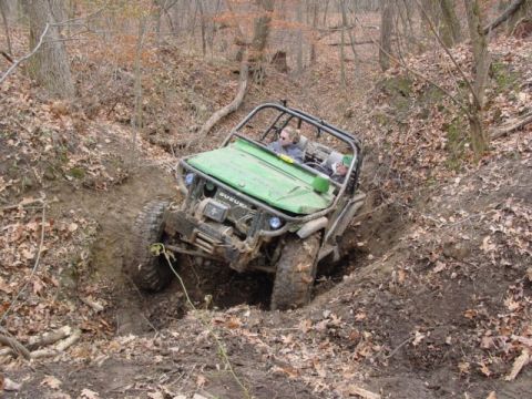 1992 Ford Bronco - A green off-road vehicle, identified by "SUZUKI" on its hood, is shown navigating a challenging muddy terrain.